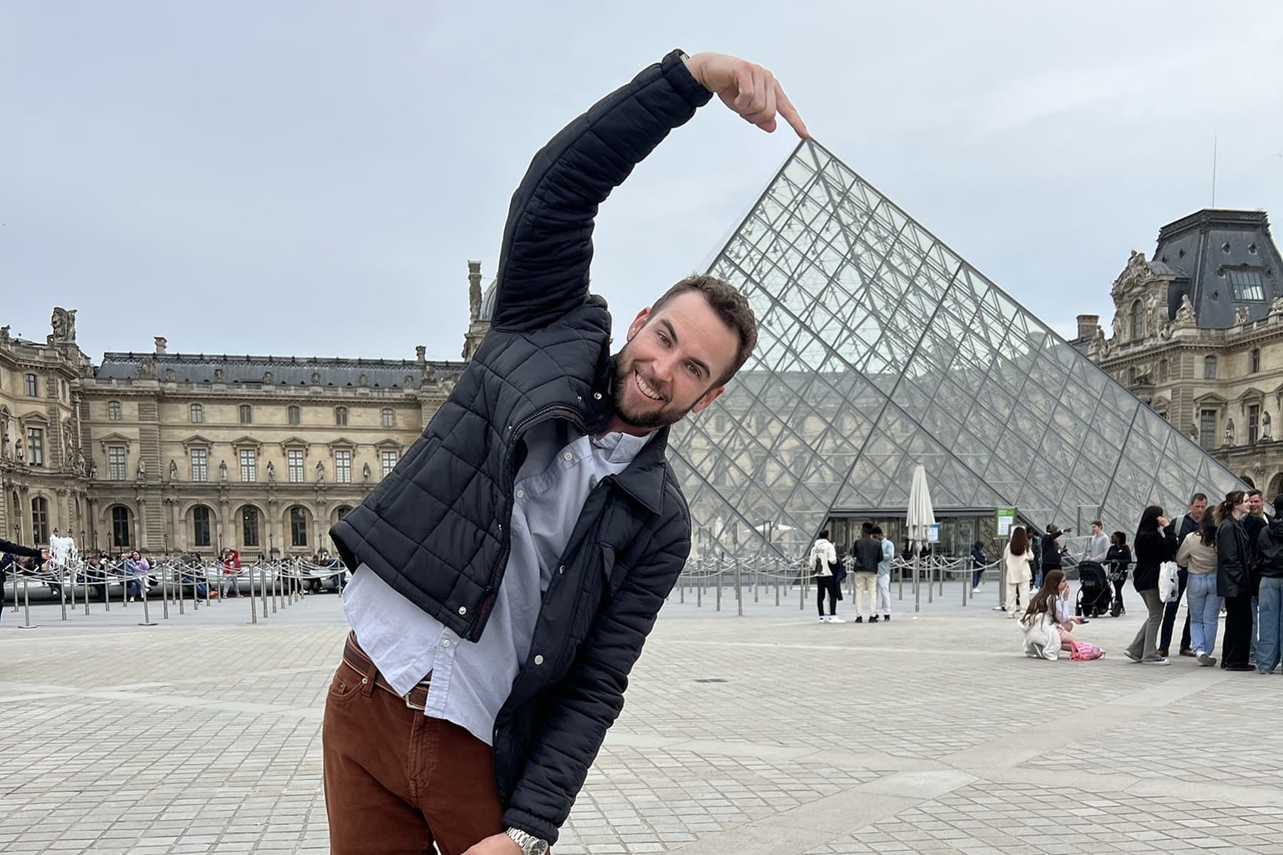 Daniel playfully 'touching' the tip of the Louvre pyramid in Paris