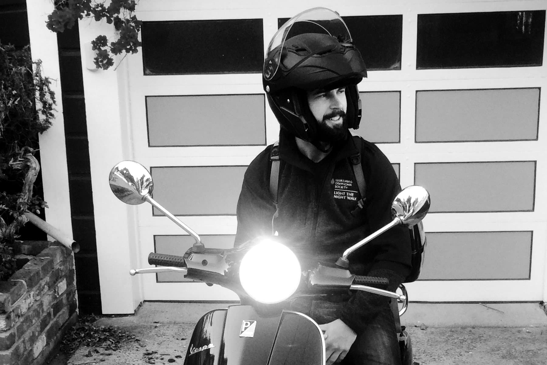 Daniel on his black Vespa, in black and white